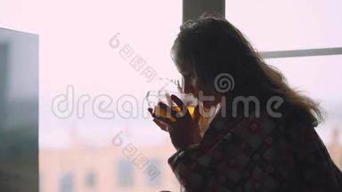 坐在窗台上喝茶的沮丧悲伤的病妇坐在窗台上，地望着窗户。 1920x1080
